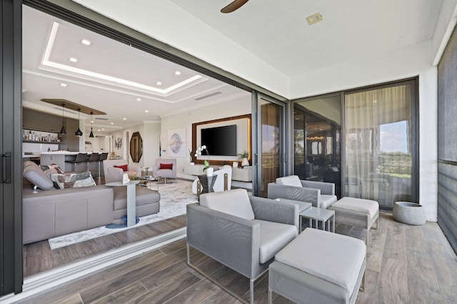 interior space featuring ornamental molding, wood-type flooring, bar area, and a raised ceiling