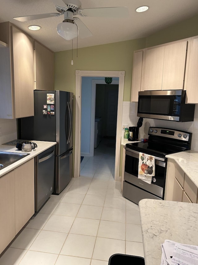 kitchen with appliances with stainless steel finishes, light countertops, light tile patterned floors, decorative backsplash, and ceiling fan