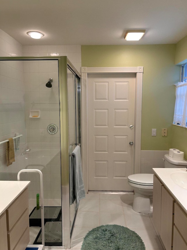 bathroom featuring tile patterned flooring, a shower with door, vanity, and toilet