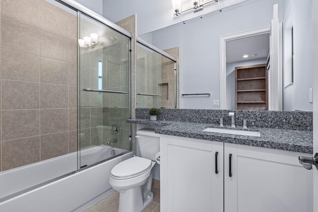 full bathroom with toilet, vanity, tile patterned floors, and bath / shower combo with glass door