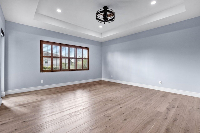 spare room with light wood-type flooring and a tray ceiling