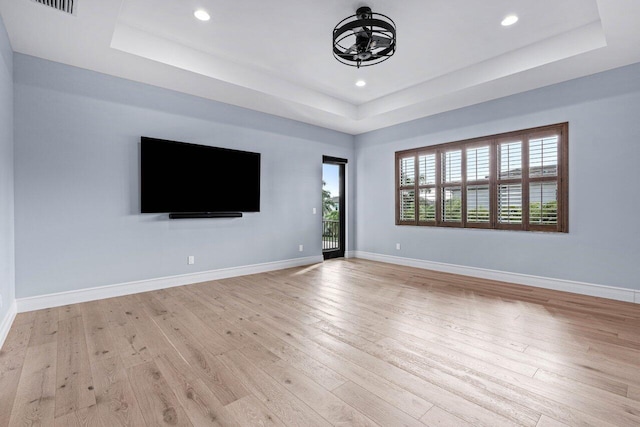 unfurnished living room featuring light hardwood / wood-style floors and a raised ceiling