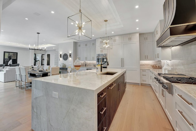 kitchen with a chandelier, a spacious island, a sink, appliances with stainless steel finishes, and a tray ceiling