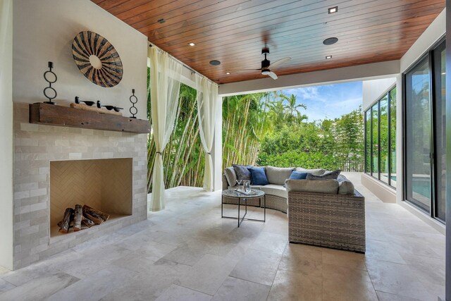 view of patio / terrace with ceiling fan and an outdoor living space with a fireplace