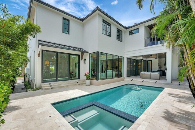 rear view of house with a balcony, a swimming pool with hot tub, a patio area, and an outdoor hangout area