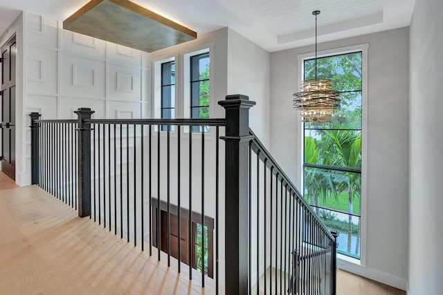 staircase featuring a chandelier, a raised ceiling, and wood finished floors