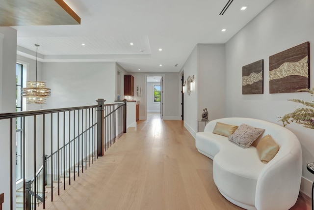 corridor featuring a tray ceiling and light wood-type flooring