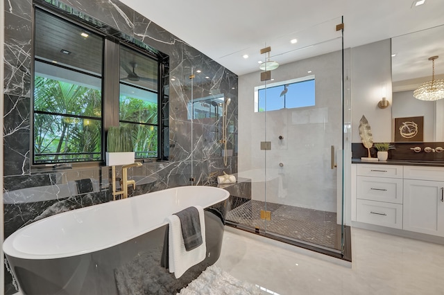 bathroom featuring plus walk in shower, tile walls, vanity, and tile patterned floors