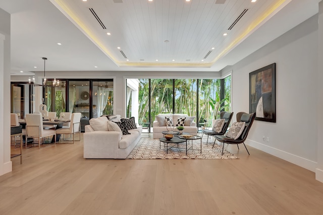 living room featuring plenty of natural light, a tray ceiling, and light hardwood / wood-style floors