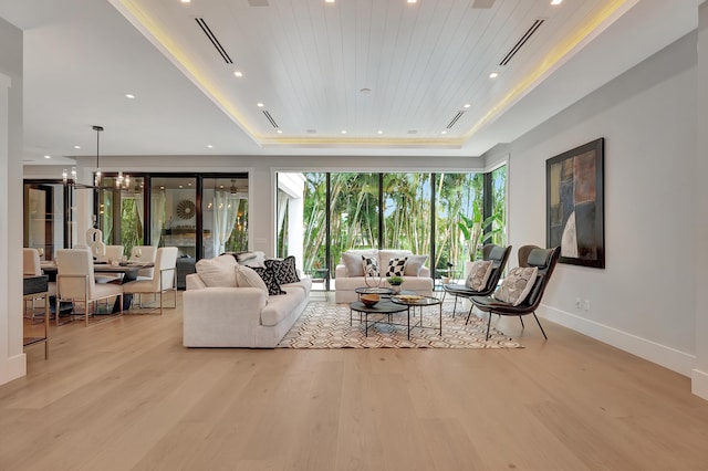 living area with a raised ceiling, wooden ceiling, baseboards, and wood finished floors