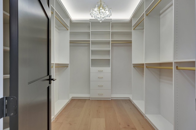 spacious closet featuring light wood-style floors and a notable chandelier