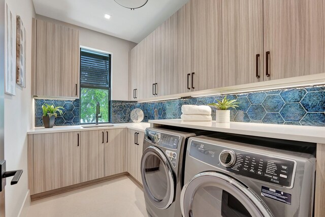 laundry room with sink, washer and clothes dryer, and cabinets