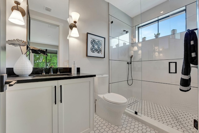 bathroom with tile patterned floors, a shower with door, vanity, and toilet