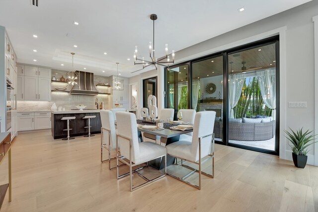 dining space with sink, light hardwood / wood-style floors, and an inviting chandelier