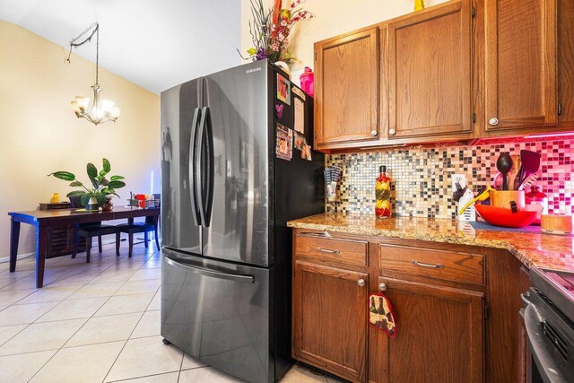 kitchen with light tile patterned flooring, tasteful backsplash, hanging light fixtures, range, and stainless steel fridge