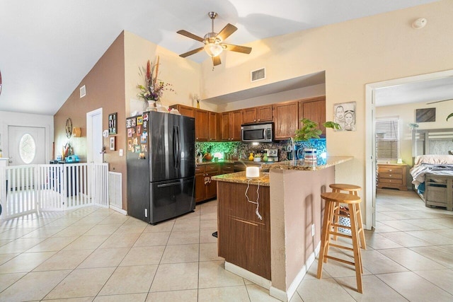 kitchen with light tile patterned floors, kitchen peninsula, ceiling fan, appliances with stainless steel finishes, and decorative backsplash