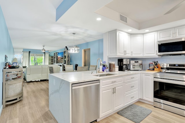 kitchen featuring sink, white cabinets, appliances with stainless steel finishes, and kitchen peninsula