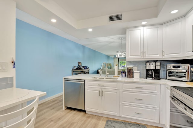 kitchen featuring stainless steel dishwasher, decorative backsplash, sink, light wood-type flooring, and white cabinets