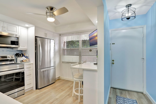 kitchen with light hardwood / wood-style flooring, pendant lighting, stainless steel appliances, and white cabinetry