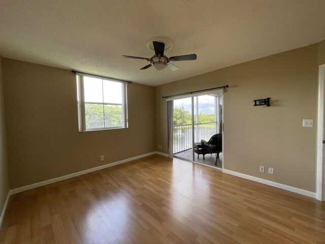 spare room featuring a textured ceiling, light wood-type flooring, and ceiling fan