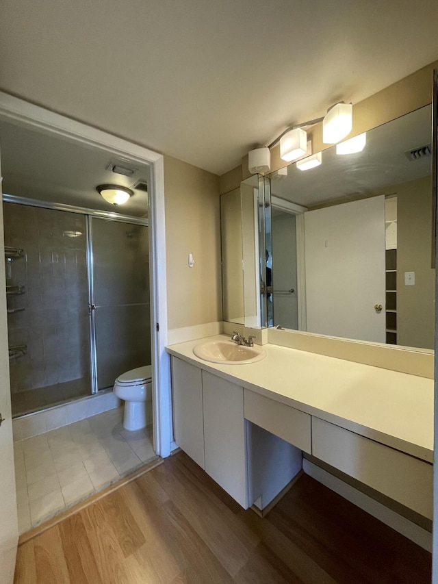 bathroom featuring toilet, vanity, hardwood / wood-style floors, and an enclosed shower