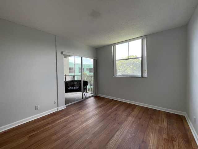 unfurnished room featuring a textured ceiling, dark wood-type flooring, and a healthy amount of sunlight