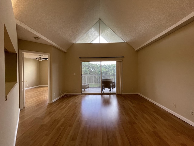 spare room featuring a textured ceiling, hardwood / wood-style flooring, and lofted ceiling