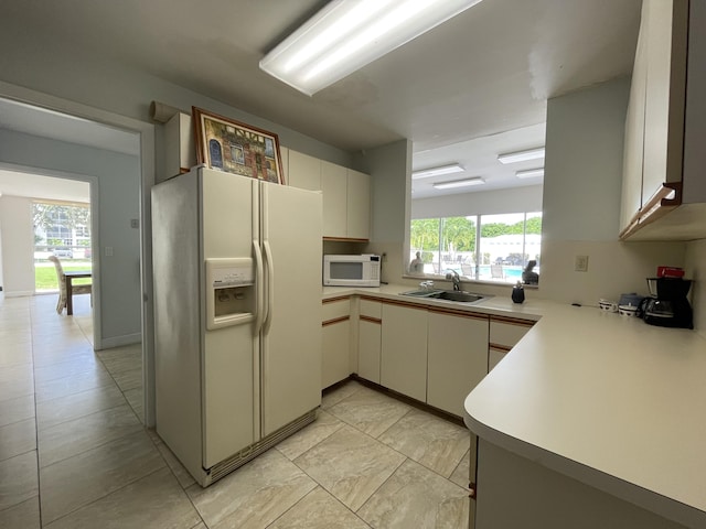 kitchen with sink, kitchen peninsula, and white appliances