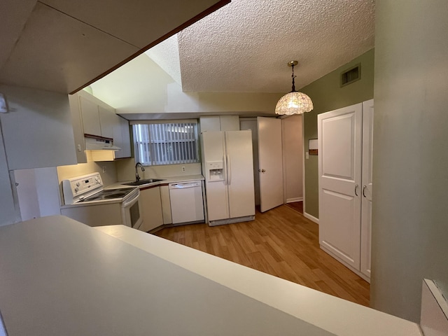 kitchen featuring light hardwood / wood-style flooring, white appliances, sink, hanging light fixtures, and a textured ceiling