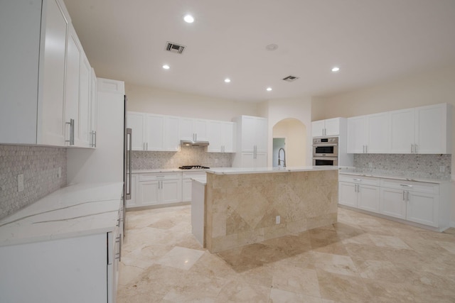 kitchen featuring white cabinetry, a center island with sink, stainless steel double oven, gas stovetop, and sink