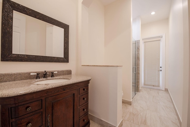 bathroom featuring a shower with shower door and vanity