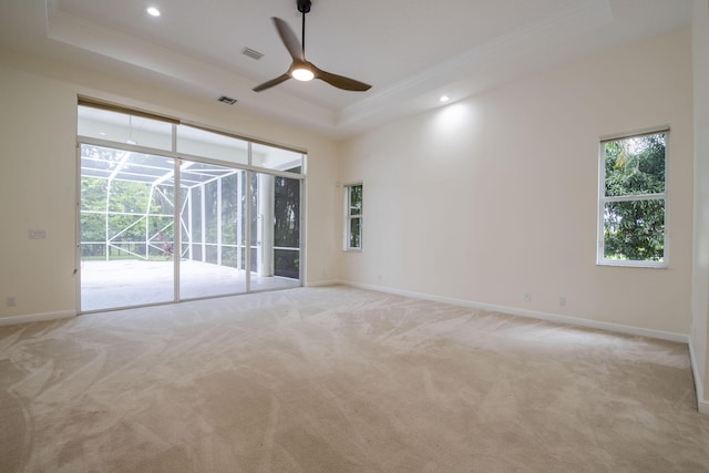 carpeted empty room featuring ceiling fan, a high ceiling, a tray ceiling, and ornamental molding