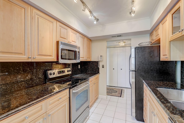 kitchen with appliances with stainless steel finishes, dark stone counters, track lighting, decorative backsplash, and ornamental molding