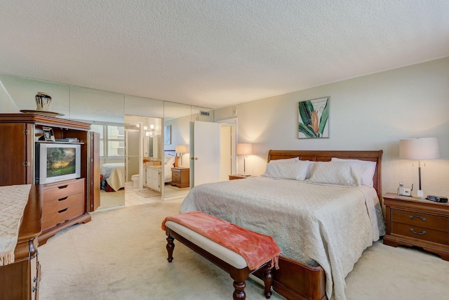 bedroom with carpet floors, ensuite bathroom, and a textured ceiling