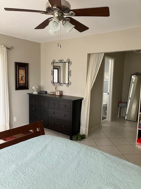 unfurnished bedroom with light tile patterned flooring, ensuite bathroom, and ceiling fan