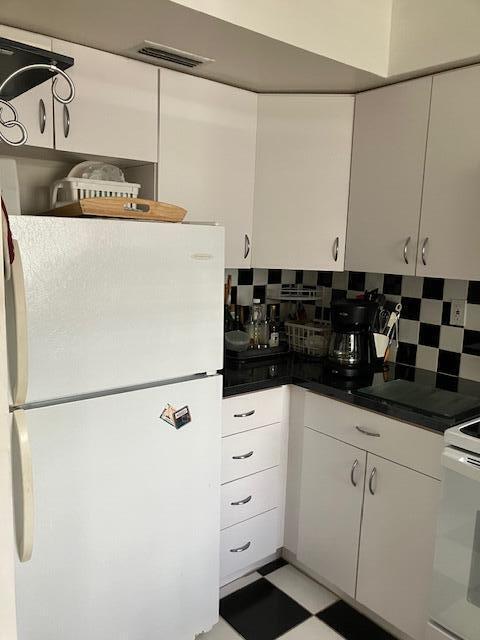 kitchen featuring white fridge, white cabinets, tasteful backsplash, and light tile patterned flooring