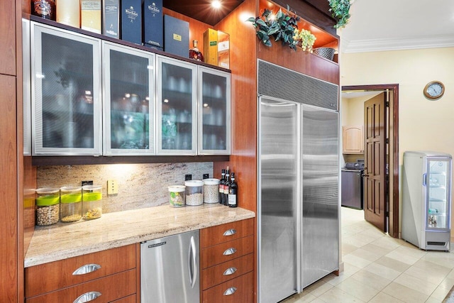 kitchen featuring stainless steel built in refrigerator, backsplash, stainless steel fridge, light stone counters, and crown molding