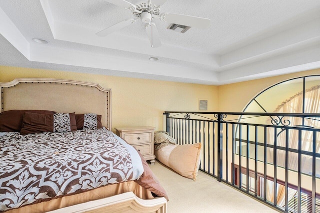 carpeted bedroom featuring ceiling fan, a textured ceiling, and a raised ceiling