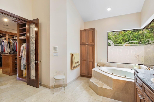 bathroom featuring tiled bath, vanity, and tile patterned flooring