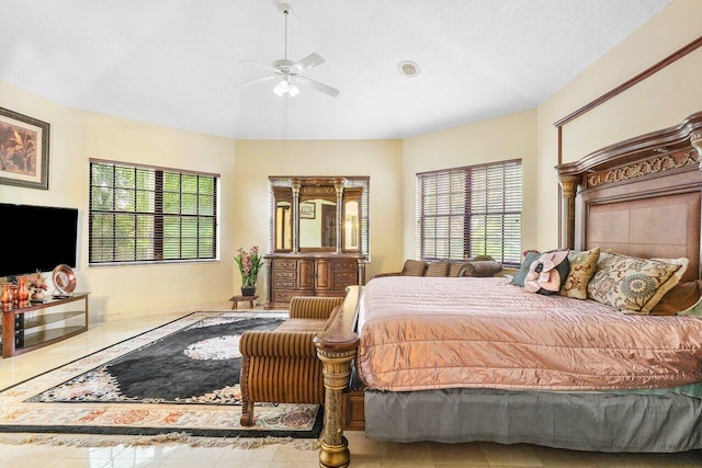 bedroom with ceiling fan, light tile patterned floors, and a textured ceiling