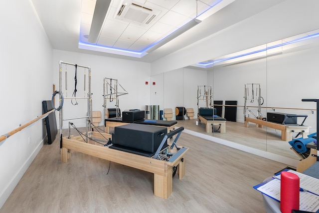 workout room with a tray ceiling and light hardwood / wood-style flooring