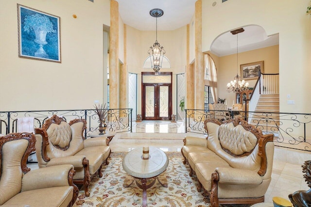 living room with a towering ceiling, french doors, crown molding, and a chandelier