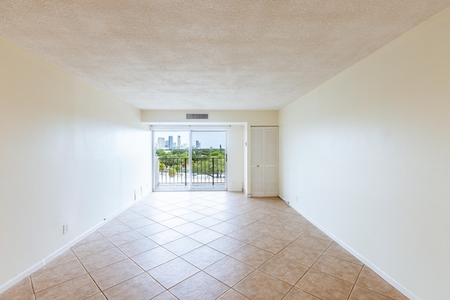 tiled empty room featuring a textured ceiling