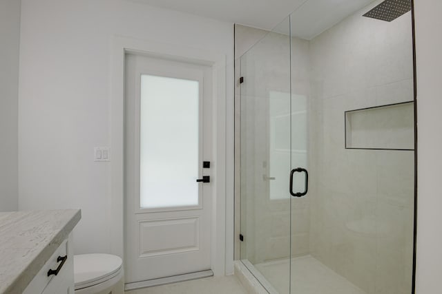 bathroom featuring a shower with door, vanity, and toilet