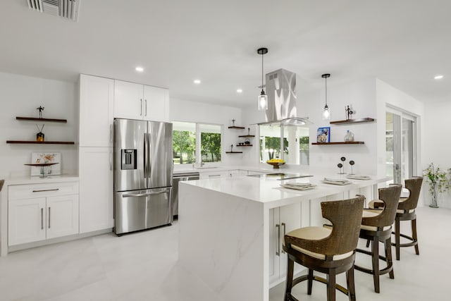 kitchen with stainless steel appliances, white cabinets, decorative light fixtures, island range hood, and a breakfast bar