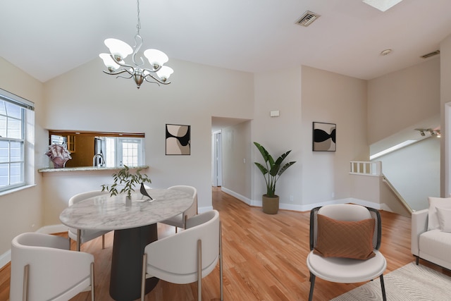 dining room with a chandelier, lofted ceiling, a wealth of natural light, and light wood-type flooring