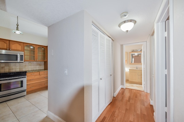 kitchen with appliances with stainless steel finishes, light hardwood / wood-style flooring, a textured ceiling, and decorative backsplash