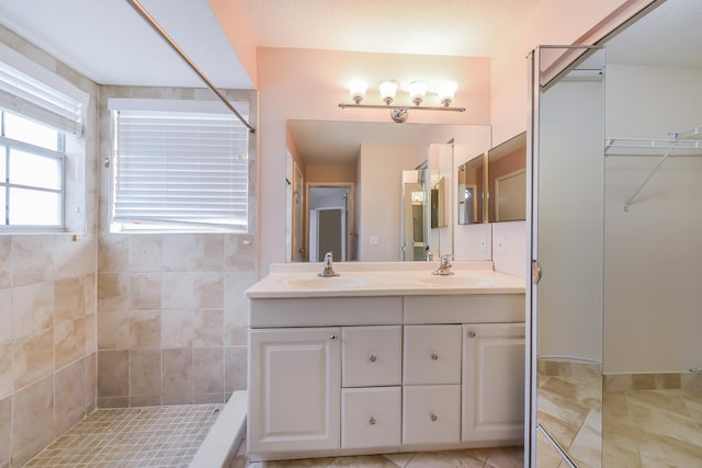 bathroom featuring a tile shower, tile patterned floors, and double vanity