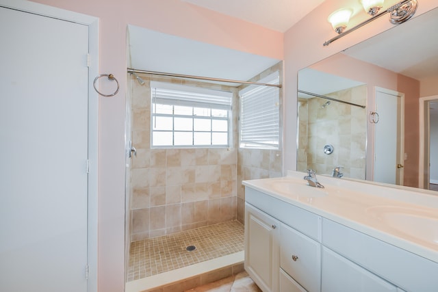 bathroom with dual vanity and a tile shower