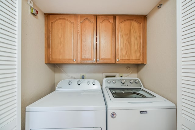 clothes washing area featuring washer and dryer and cabinets